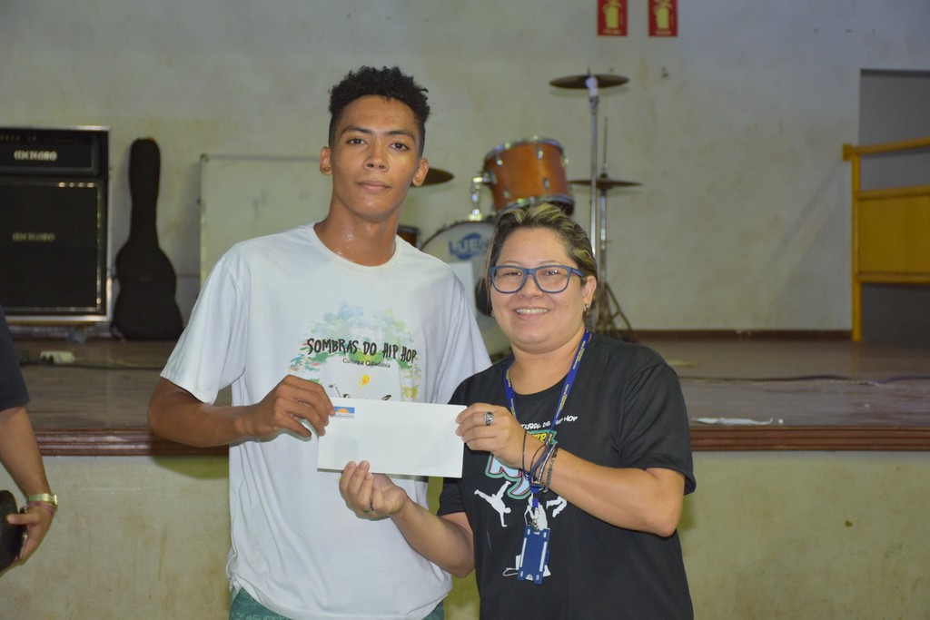 A servidora do MPE, Laidylaura de Araújo, entrega premiação a Warley Carvalho, vencedor da batalha de B-boys.